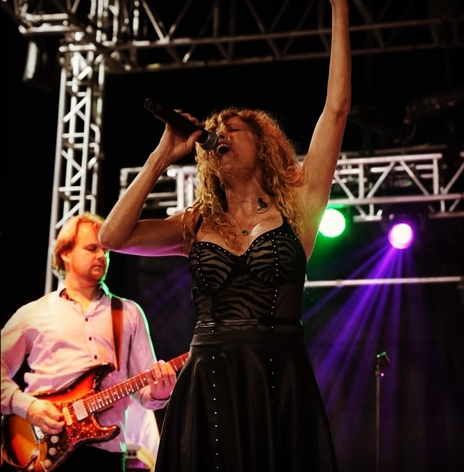A man is singing into a microphone while playing a guitar.