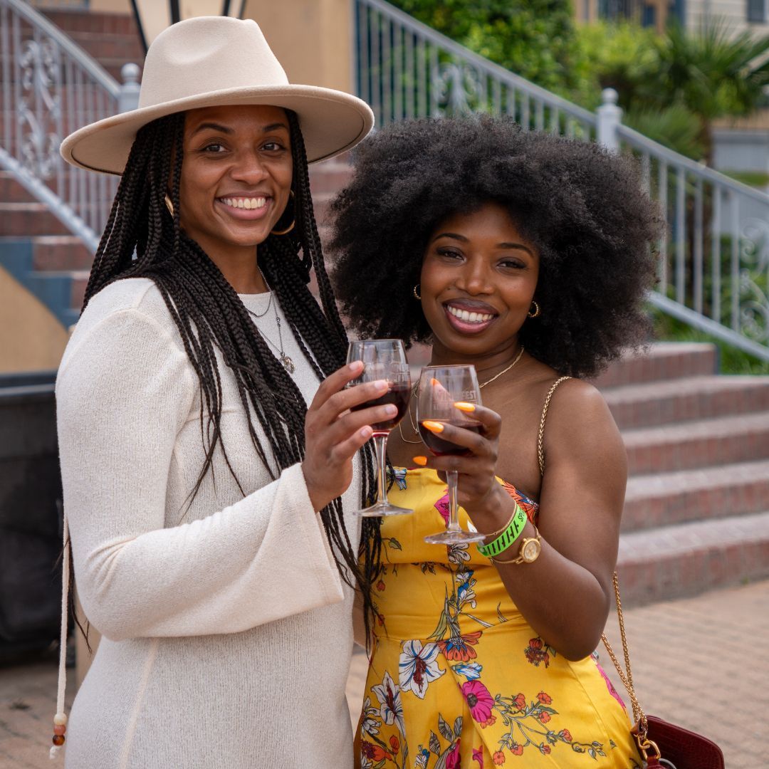 A man and a woman are posing for a picture while holding wine glasses