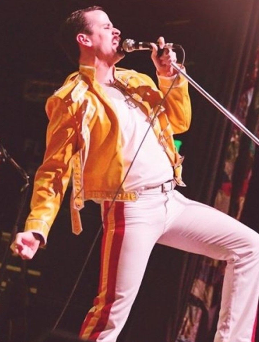 A man in a yellow jacket is singing into a microphone