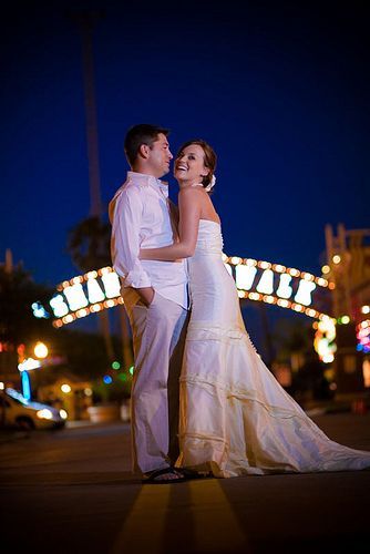A bride and groom are posing for a picture in front of a sign that says kemah boardwalk