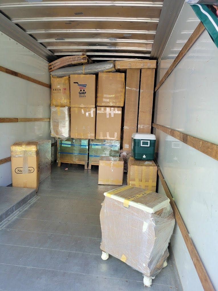The inside of a moving truck filled with boxes and a green cooler