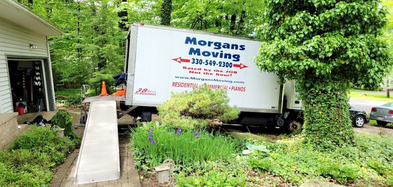 A morgans moving truck is parked in front of a house.