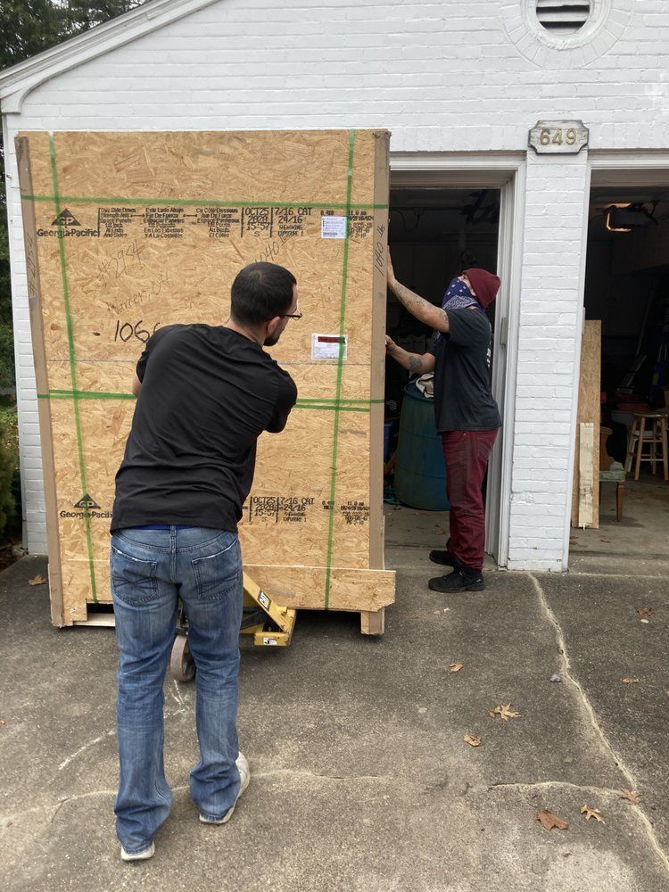 Two men are loading a large wooden box into a garage.