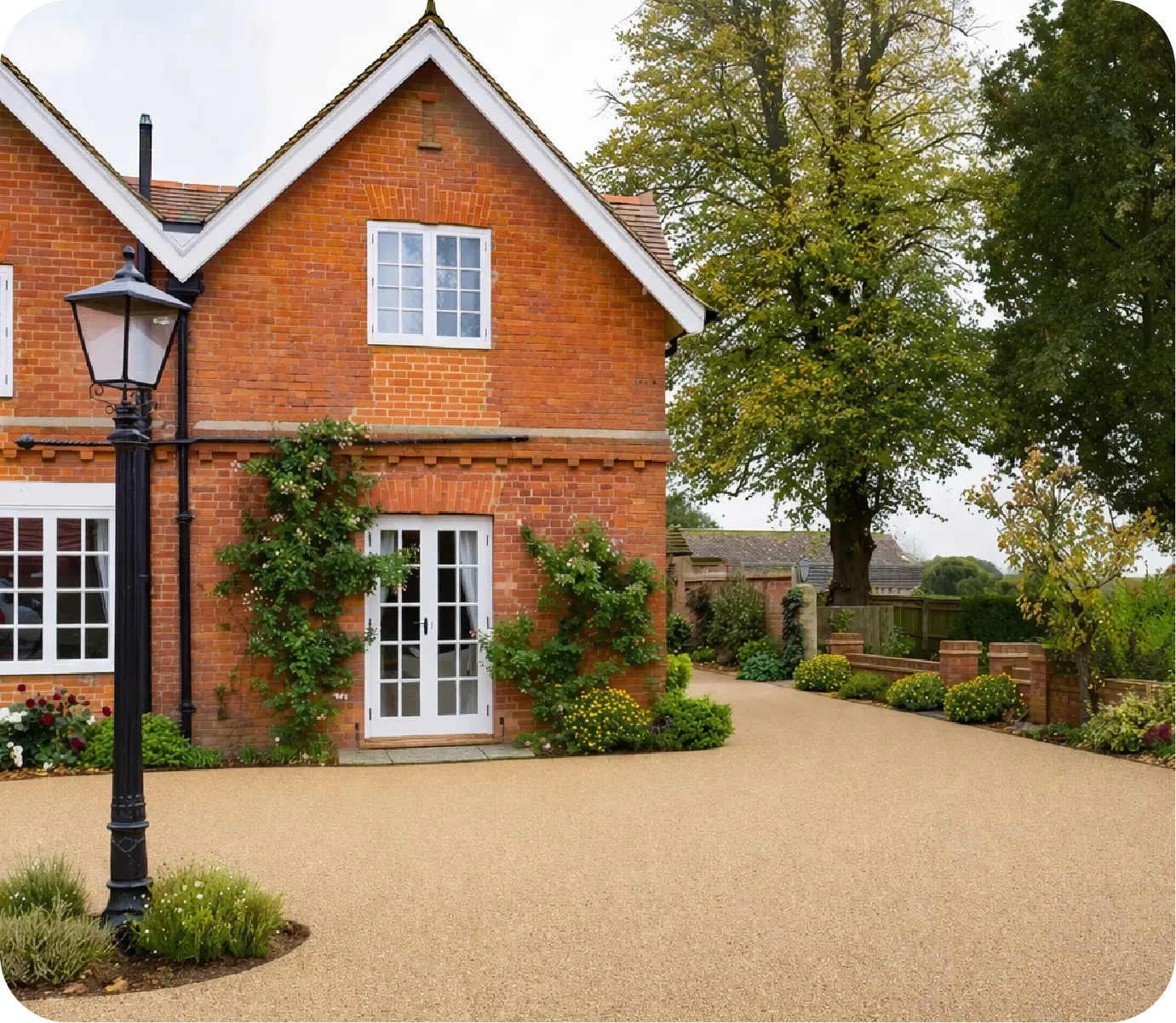 A two-story brick house with a gravel driveway, white-framed doors and windows, and a vintage-style lamp post.