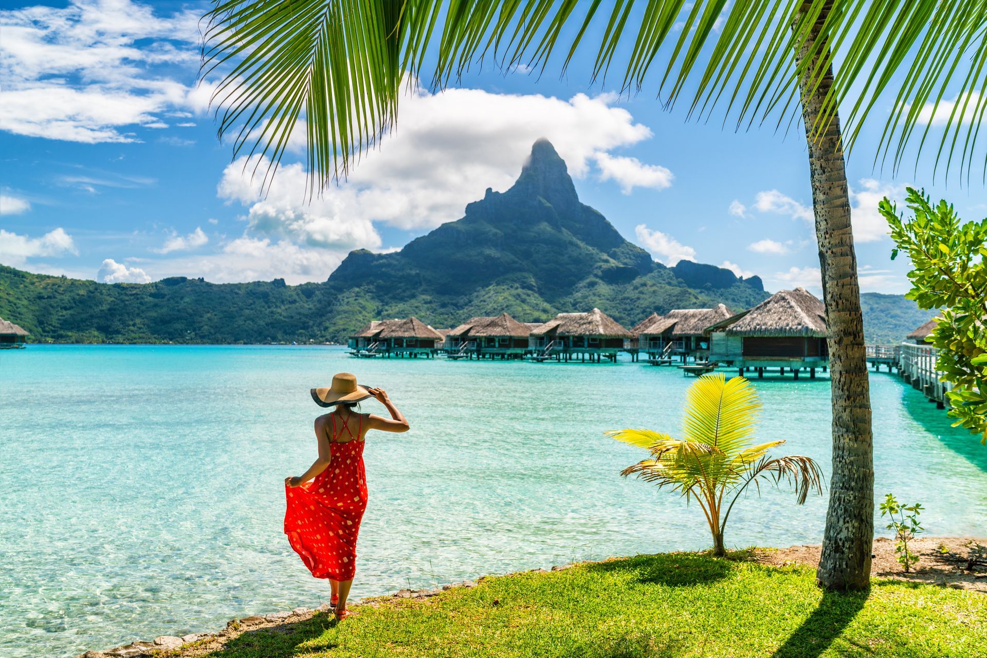 Female tourist walking on Bora Bora Island beach with view of Mt. Otemanu.