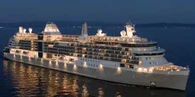 A cruise ship at night, with illuminated lights on the water.