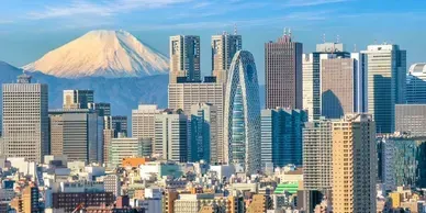 City skyline with Mount Fuji in the background on a sunny day.