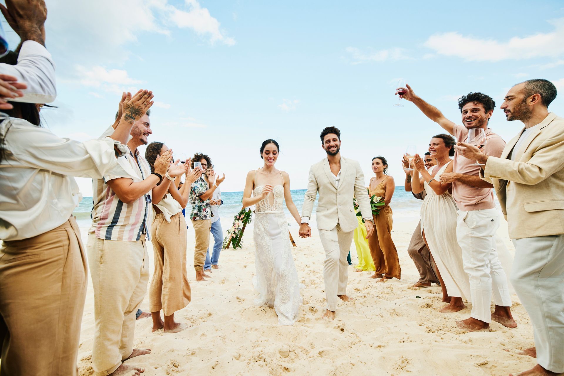The bride is placing a wedding ring on the groom's finger, both in formal attire.