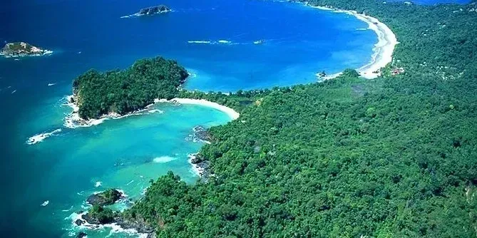 Aerial view of a tropical coastline with lush green forest, turquoise waters, and sandy beaches.