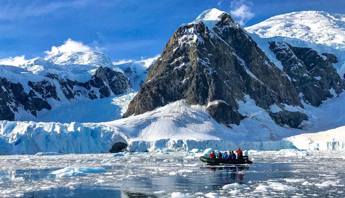 A boat with people navigating icy water in Antarctica.