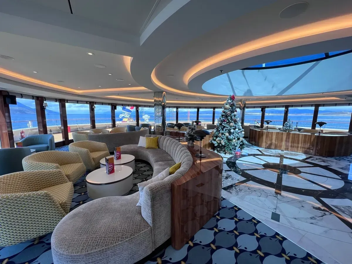 A circular lounge with sea views, featuring curved seating, a bar, and a Christmas tree.