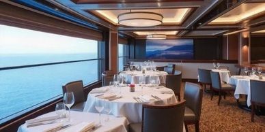 Elegant restaurant with ocean views; tables set, diners absent.
