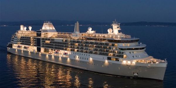 Cruise ship sailing on dark water at dusk.