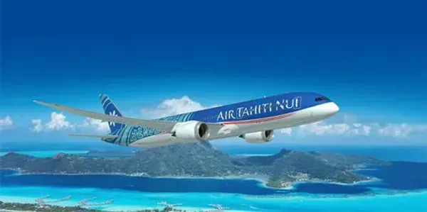 An airplane ascending in a bright blue sky, with white contrails trailing behind.