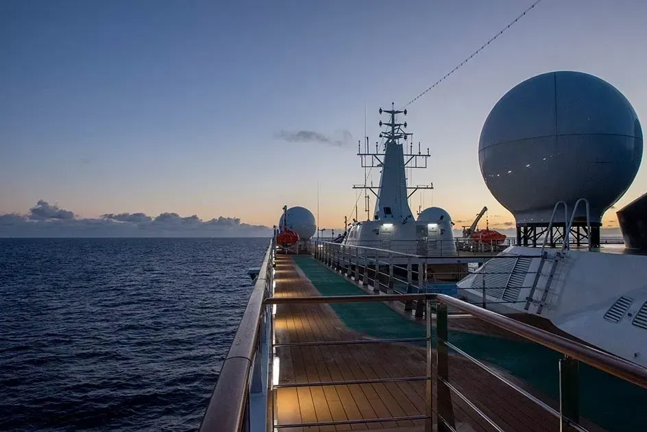 Deck of a ship at dusk, with a view of the ocean and satellite domes.