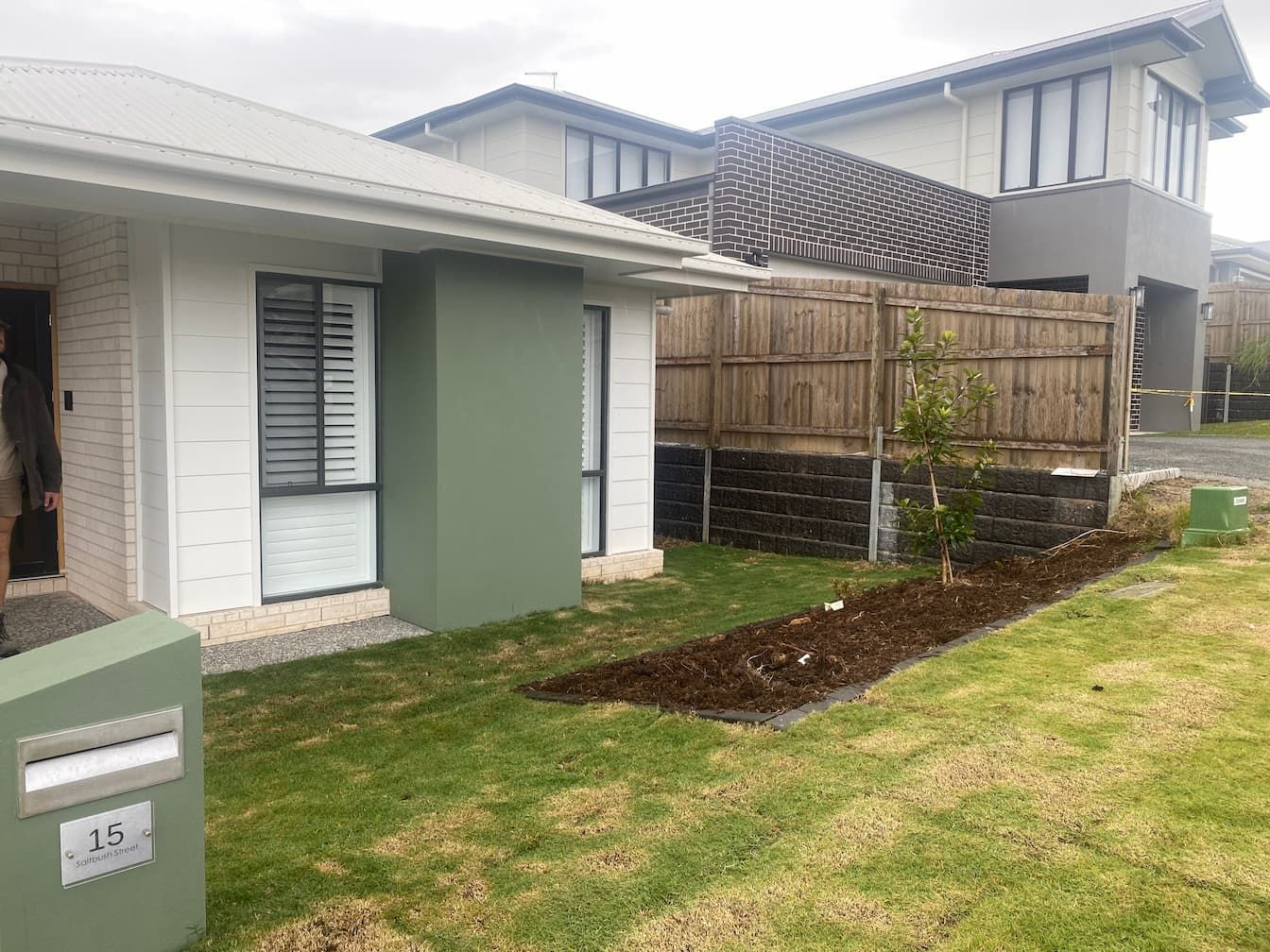 A white house with a green fence and a mailbox in front of it.