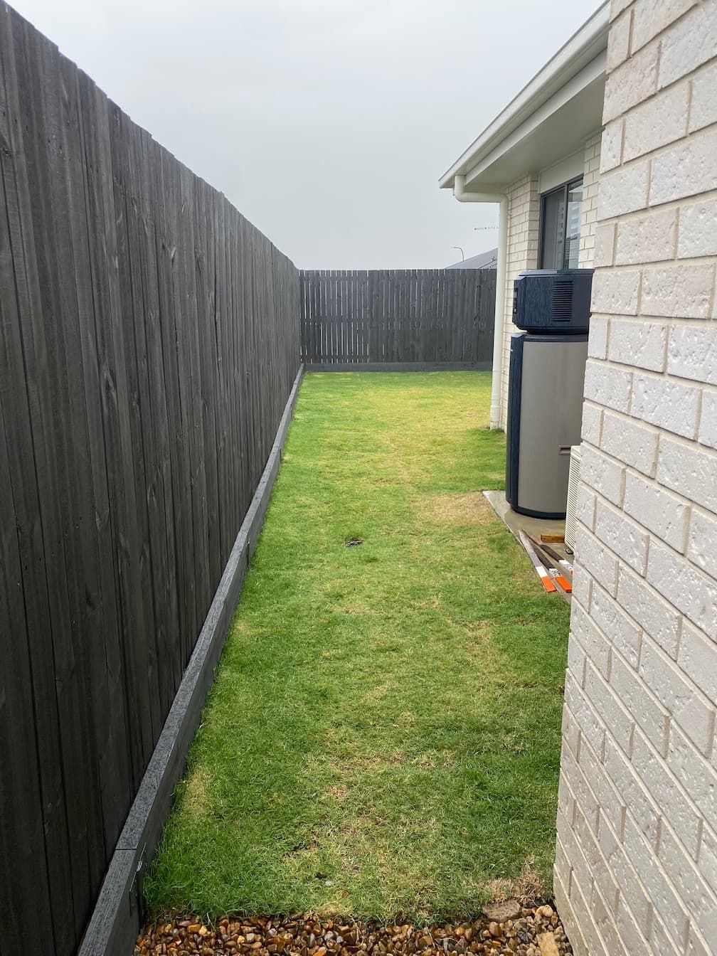 A backyard with a wooden fence and a brick wall.