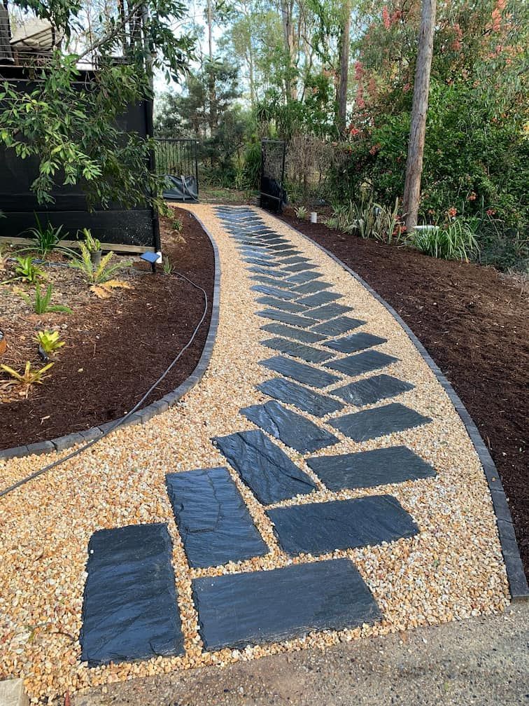 A walkway made of slate tiles and gravel in a garden.