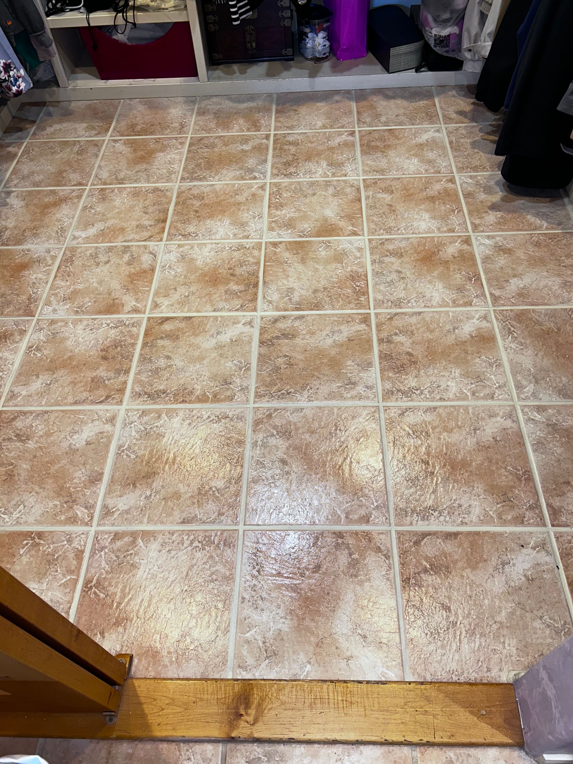 Tiled kitchen floor with a wooden threshold and storage items along the edges