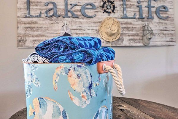 A basket full of beach towels in front of a sign that says Lake Life