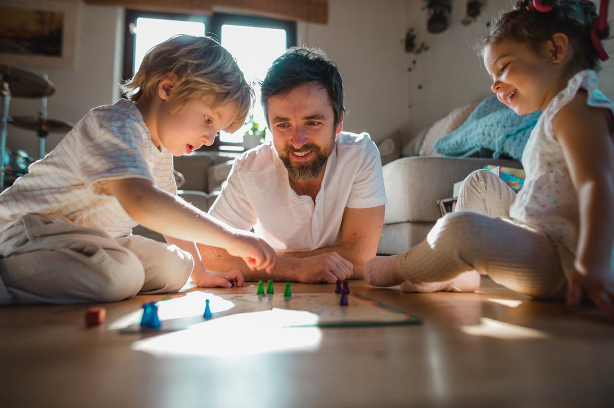 An example of a positive vacation rental scene is a father playing a board game with his children.