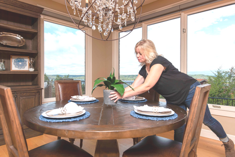Holly Jones of Branson Upstaging placing a vase on a dinning table during a home decorating project
