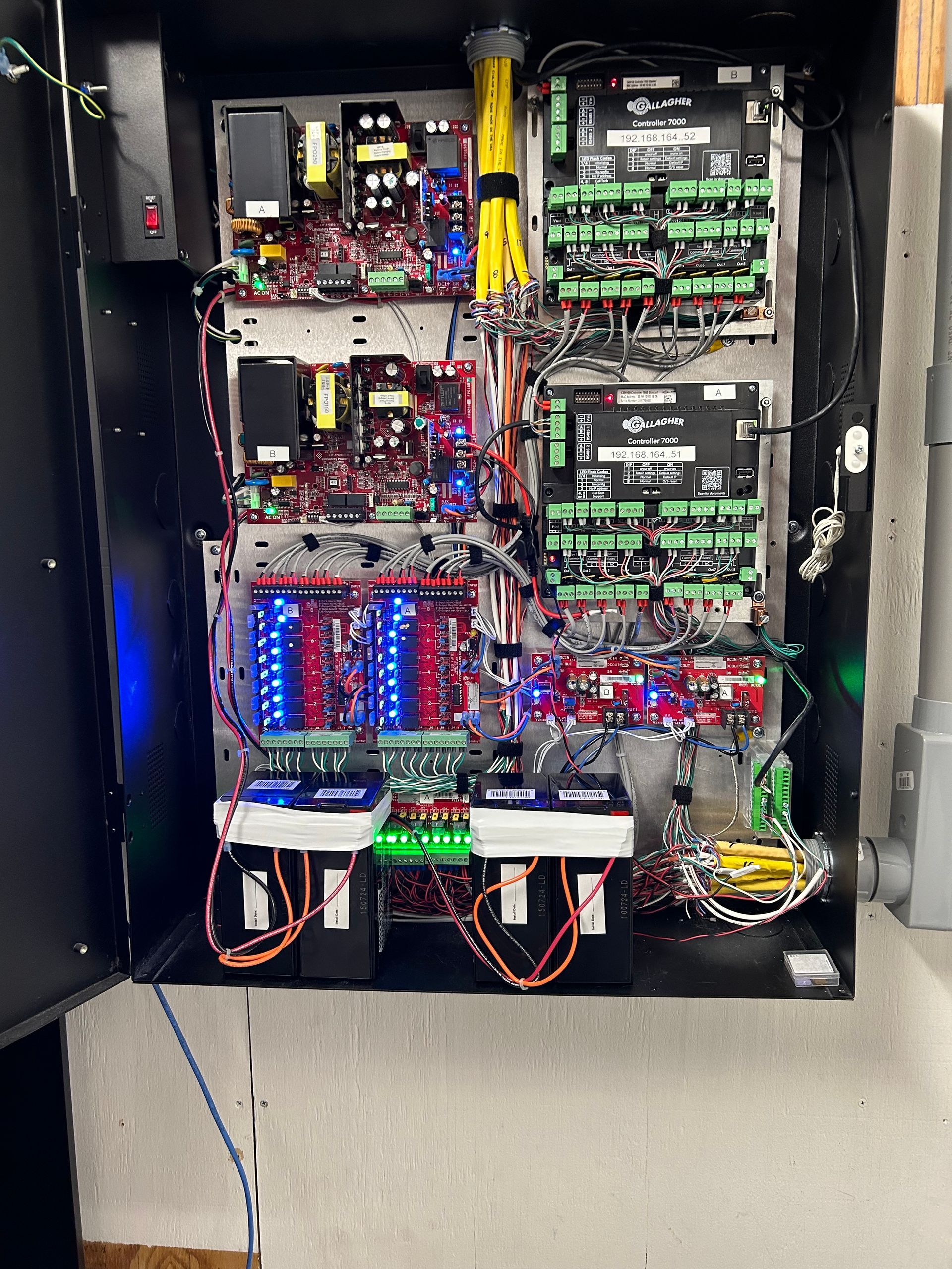 Opened black electrical panel with complex wiring, LEDs, and circuit boards.