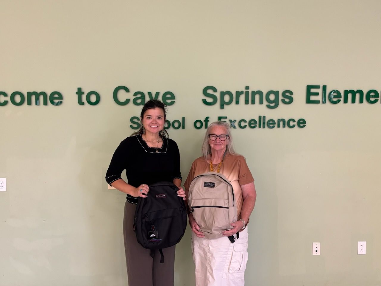 two Lady's holding backpacks that were donated 