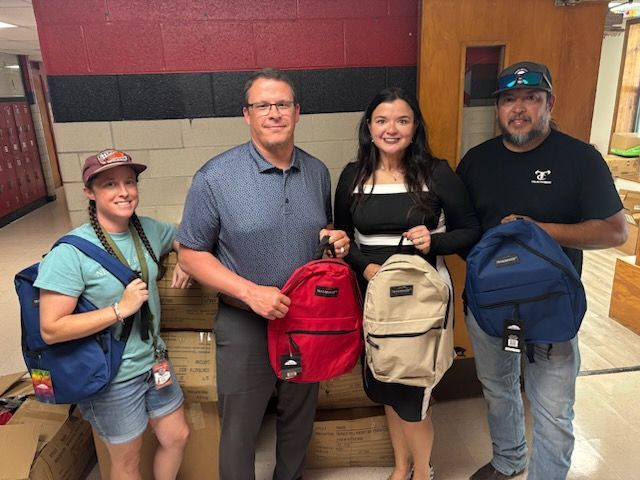 Four People holding donated backpacks 