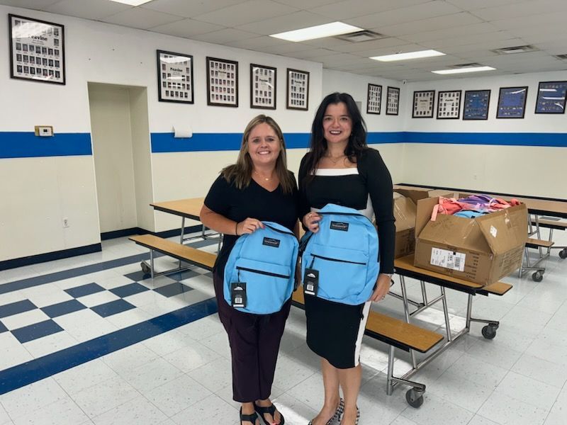 two Women Holding backpacks that were donated