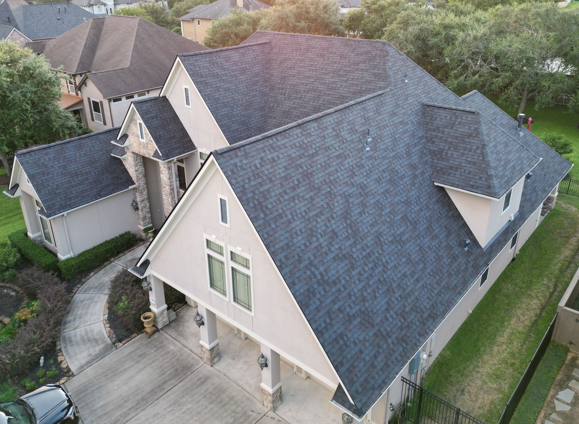 A roofing and construction sign is in front of a house.