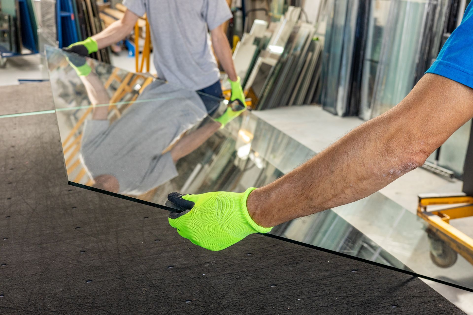 Two glaziers holding a large sheet of thick glass by hand. Two glaziers holding a large sheet of thick glass by hand.