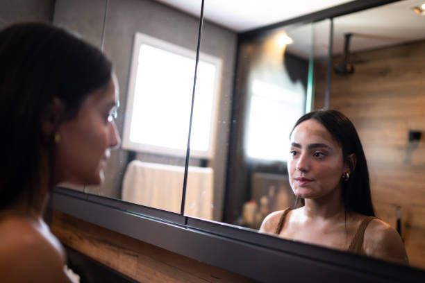 A woman looking at the mirror in her bathroom. 