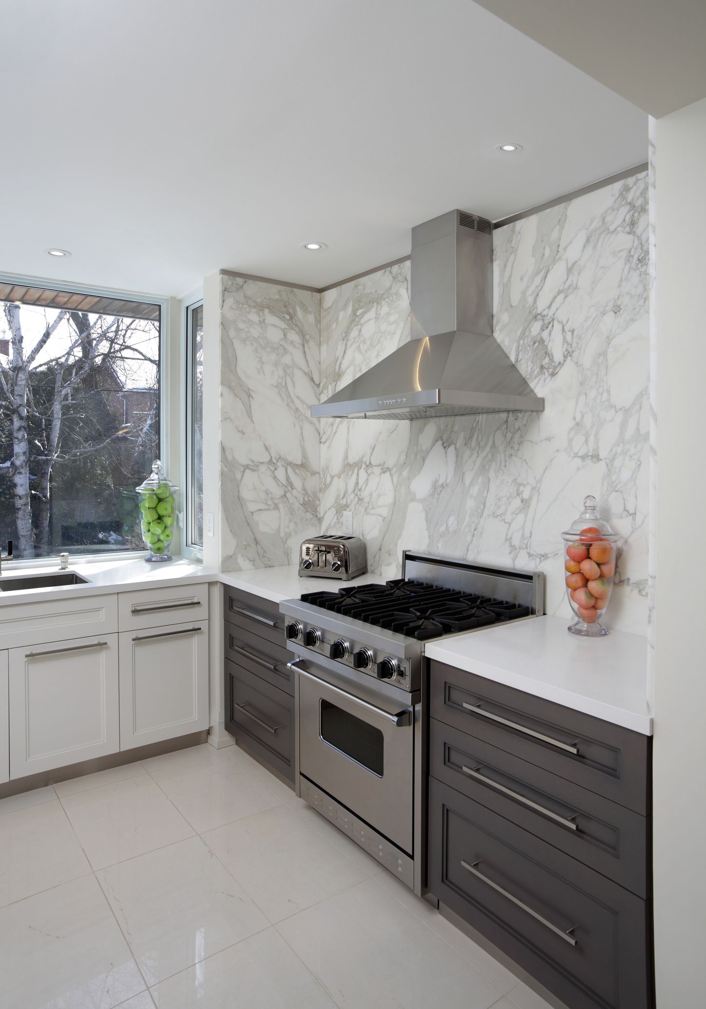 Modern kitchen with stainless steel range, marble backsplash, and white and gray cabinets. Modern kitchen with stainless steel range, marble backsplash, and white and gray cabinets.
