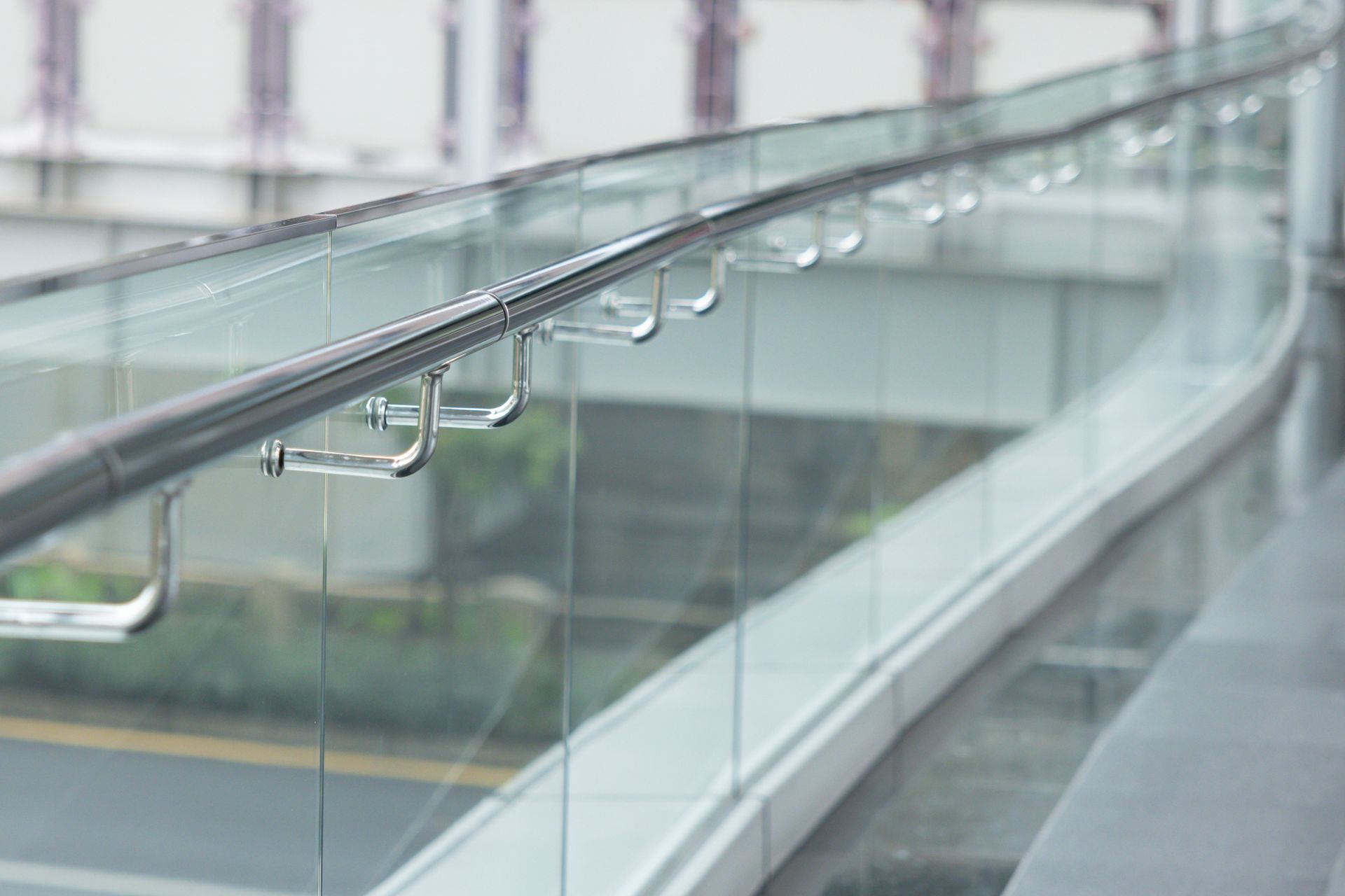Modern glass balustrade with metal brackets and steel handrail for sleek architectural design. Modern glass balustrade with metal brackets and steel handrail for sleek architectural design.