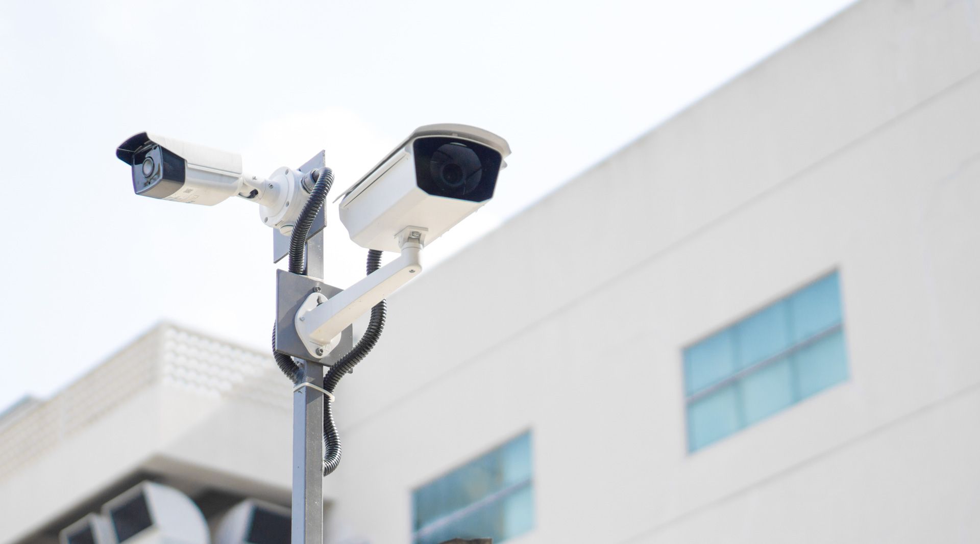 A person is installing a security camera on a wall.