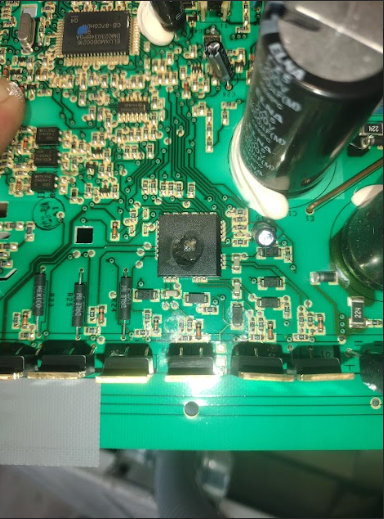Green circuit board with a burnt-out component and various other electronic parts.