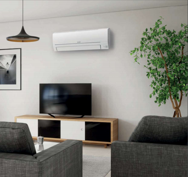 Soggiorno moderno con condizionatore d'aria su una parete bianca sopra un televisore e una pianta verde in vaso.