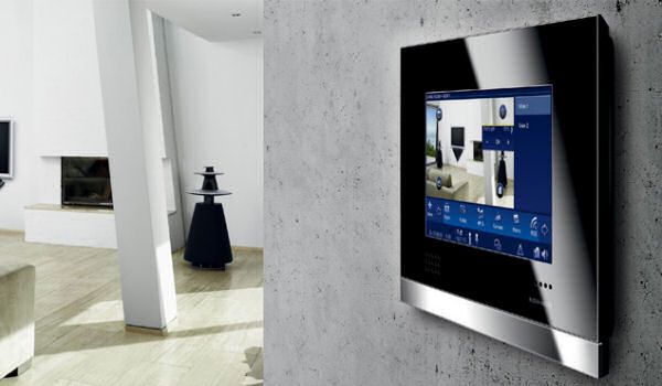 Un elegante pannello di controllo touchscreen a parete per la domotica, che visualizza le immagini delle telecamere di sicurezza in un moderno soggiorno.