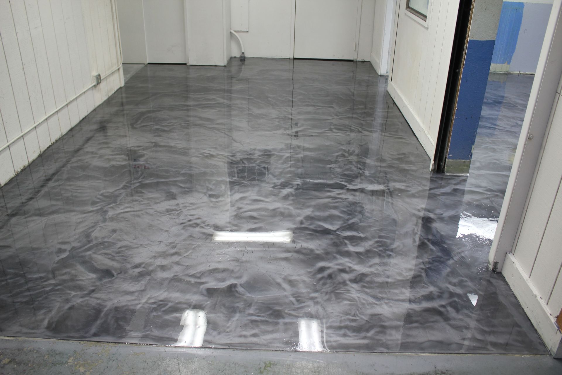 A shiny metallic floor in a room with a door.