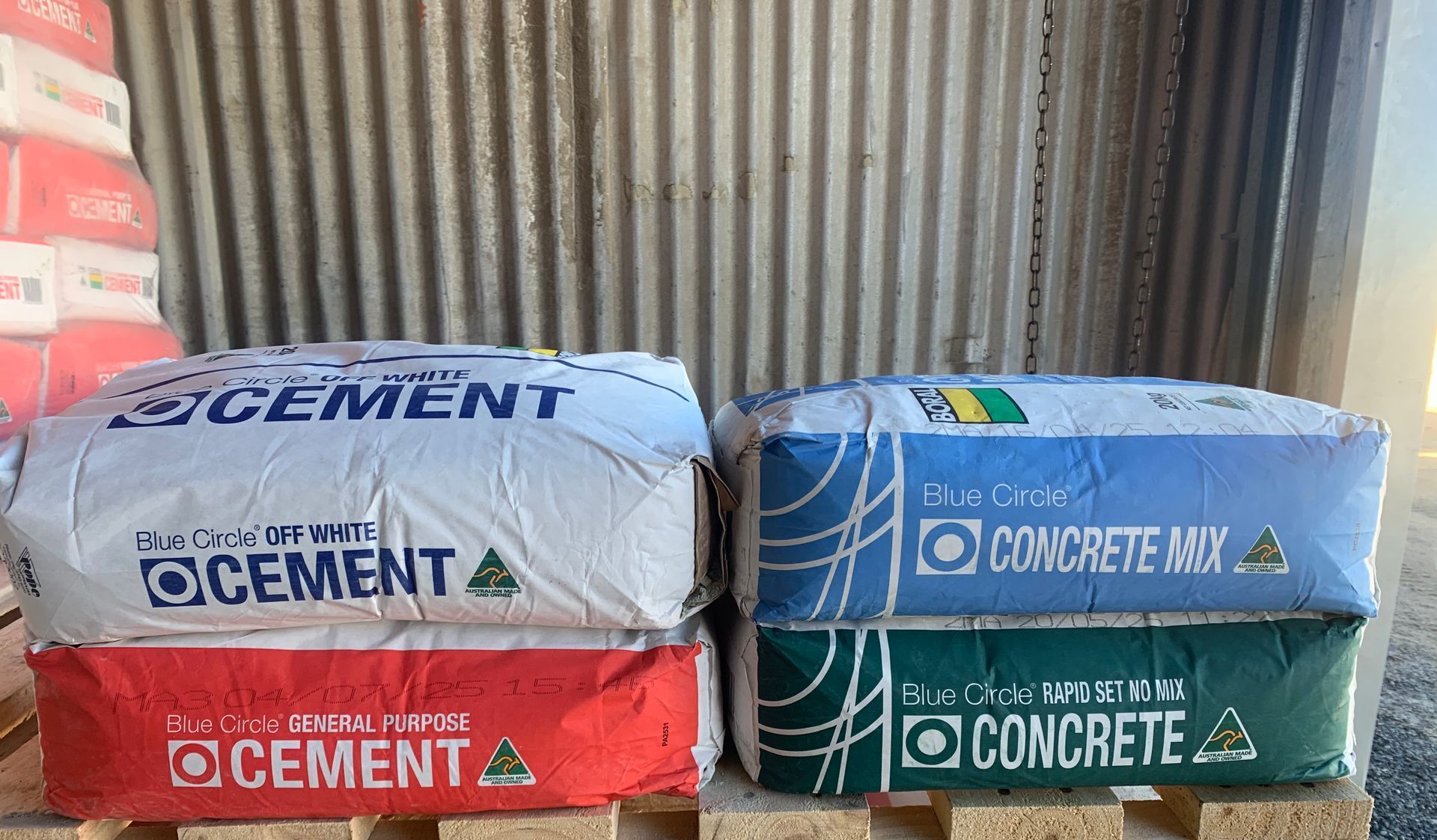 Two bags of cement and concrete mix on a wooden pallet, blue and white bags stacked on pallets — Frost 4 Sand In West Gosford, NSW