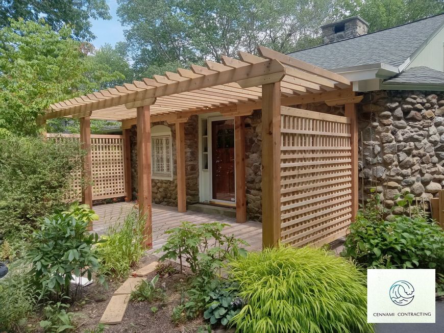 Wooden pergola over a stone facade entrance with lattice side panels and surrounding greenery.