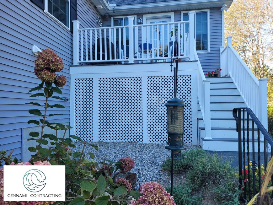 White deck with latticework and stairs attached to a house with gray siding.