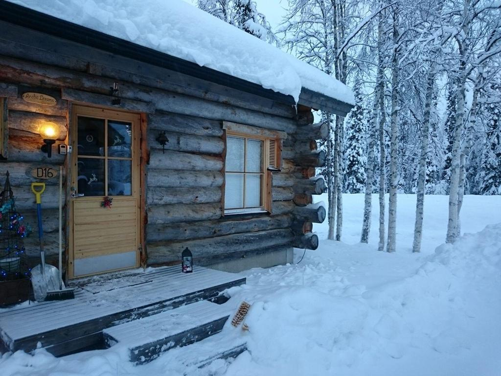 A log cabin covered in snow in the middle of a snowy forest in lapland