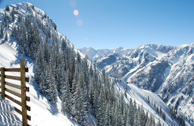 A snowy mountain range in Aspen with a wooden fence in the foreground