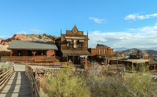 A wooden building in the calico ghost town, in the middle of a desert with mountains in the background.