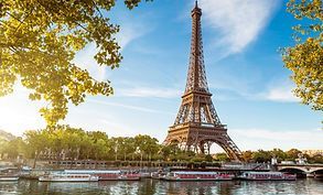 The eiffel tower is surrounded by trees and boats in paris.