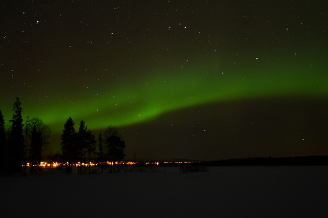 The aurora borealis is dancing in the night sky over a lake in lapland