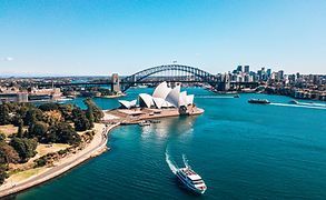 An aerial view of sydney harbor with the opera house and the harbor bridge in the background.