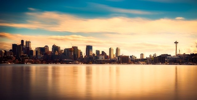 The city skyline of Seattle is reflected in the water at sunset.